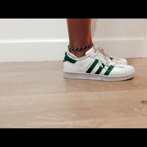 Green and white Adidas superstars